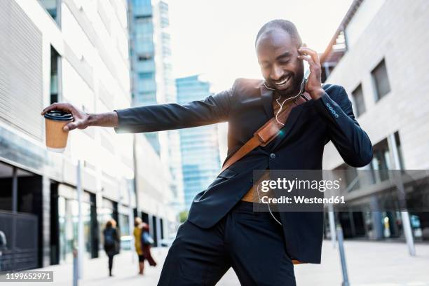 portrait of happy young businessman dancing on the street while listening music with earphones - leisure work coffee happy stockfoto's en -beelden