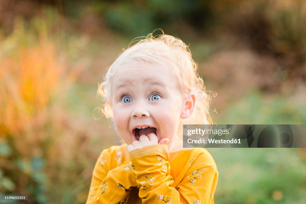 Portrait of blond toddler girl with blue eyes pulling funny faces