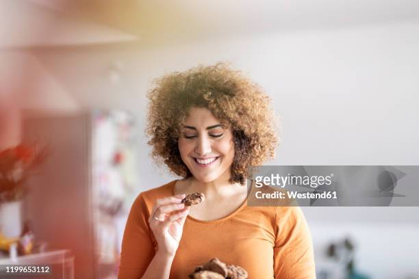 smiling mid adult woman eating a cookie - bites stock pictures, royalty-free photos & images