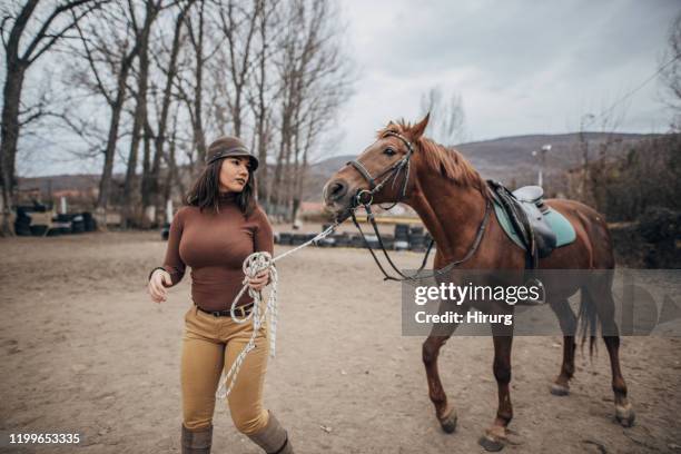 junge weibliche jockey bereit, pferd zu reiten - animal trainer stock-fotos und bilder