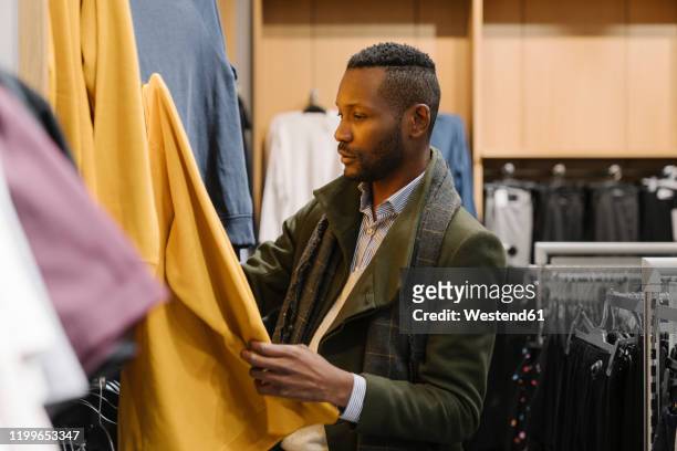 stylish man shopping in a clothes store - abbigliamento da uomo foto e immagini stock