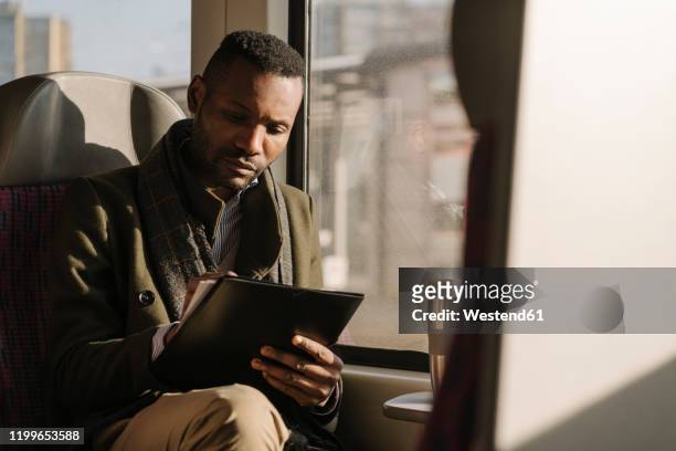 stylish businessman taking notes while traveling by train - travel writer stock pictures, royalty-free photos & images