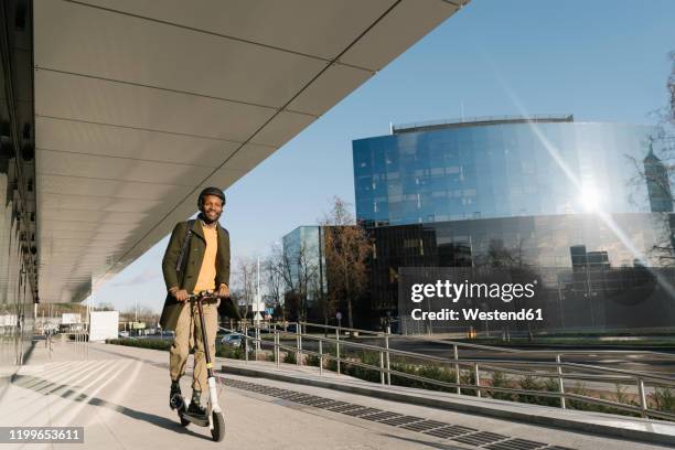 stylish man with helmet riding a scooter in the city - tretroller stock-fotos und bilder