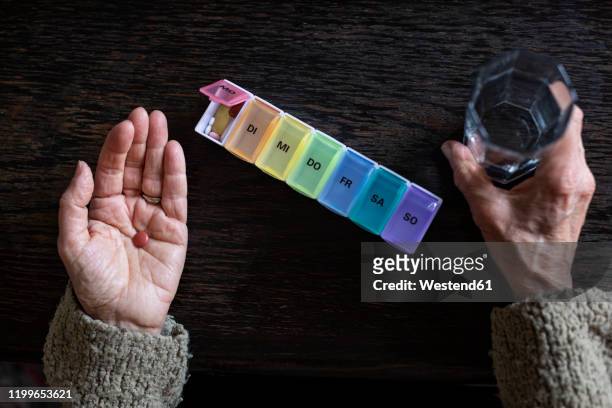 senior woman taking medicine, water glass and pill organiser - dosing stock-fotos und bilder