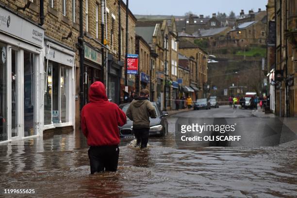 People wade through floodwater in the streets of Hebden Bridge, northern England, on February 9 as Storm Ciara swept over the country. - Britain and...