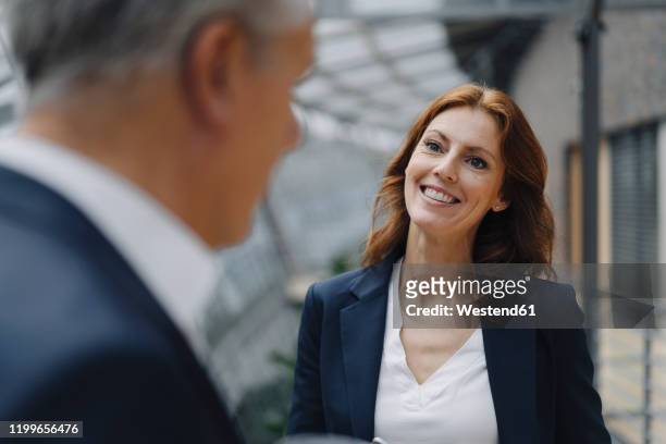 portrait of smiling businesswoman talking to businessman in office - business woman talking stock-fotos und bilder