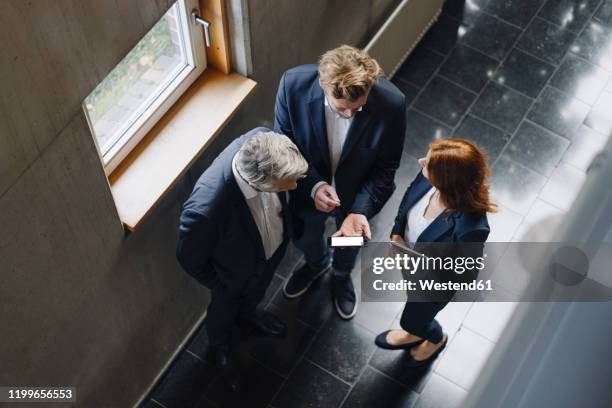 business people with smartphone talking in modern office building - telefonberatung stock-fotos und bilder