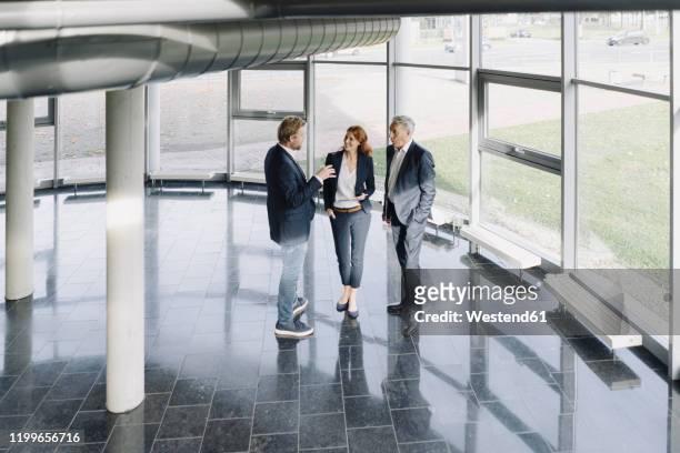 business people talking at the window in modern office building - advice column stock pictures, royalty-free photos & images