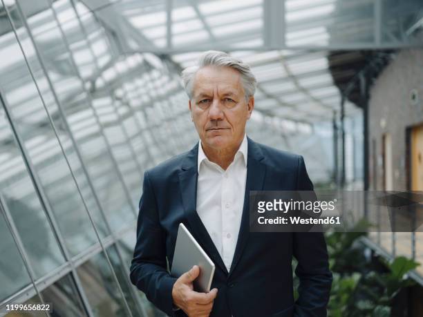 portrait of a serious senior businessman with tablet in office - elegante kleidung stock-fotos und bilder