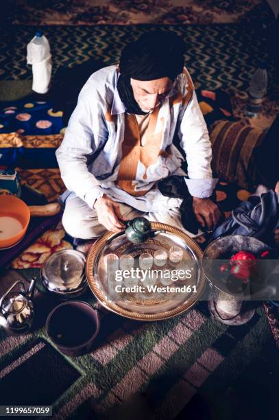 senior man in smara refugee camp pouring tea into glasses, tindouf, algeria - berbere - fotografias e filmes do acervo