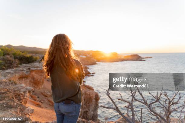 redheaded young woman standing at the coast at sunset, ibiza, spain - ginger bush stock pictures, royalty-free photos & images