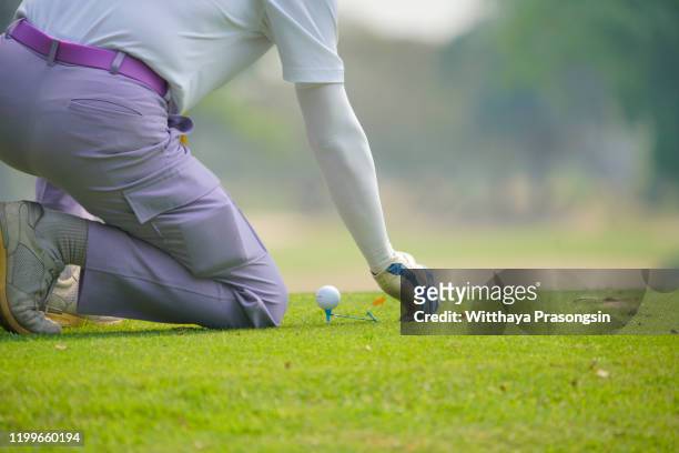 putting golf ball on tee with club in golf course on evening and sunset time a for healthy sport. lifestyle concept - golf swing close up stock pictures, royalty-free photos & images