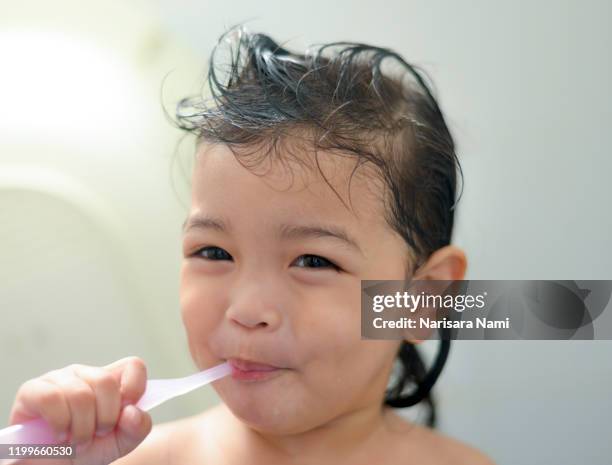 dental hygiene. asian cute girl or kid brushing her teeth by toothbrush in the bathroom. healthcare concept. - mouthwash stock-fotos und bilder