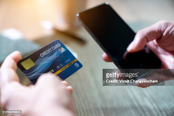 hands holding credit card and smartphone for online payment for goods and services - phone credit card stock-fotos und bilder