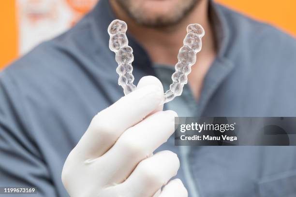 detail of a man's hand with white gloves showing some transparent brackets - invisible braces stock pictures, royalty-free photos & images