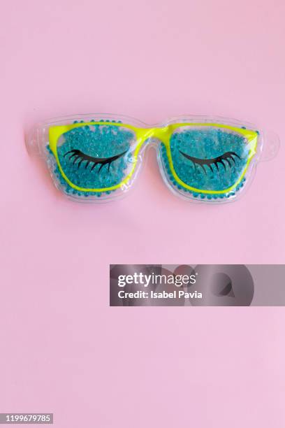 blue eye mask on pink background - false eyelash stock-fotos und bilder