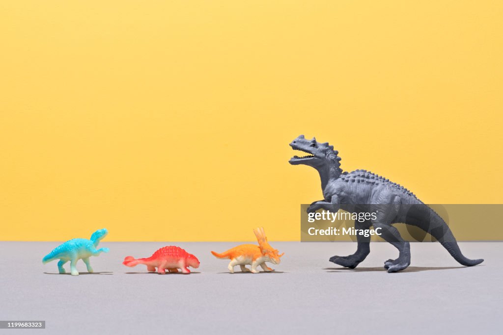 Small Toy Dinosaurs Facing A Large Toy Dinosaur