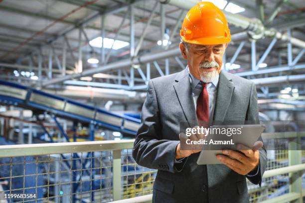 working senior using digital tablet in recycling facility - digital catwalk stock pictures, royalty-free photos & images