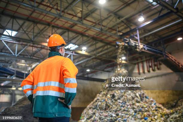 lavoratore che osserva il trattamento dei rifiuti presso l'impianto di riciclaggio - centro di riciclaggio foto e immagini stock