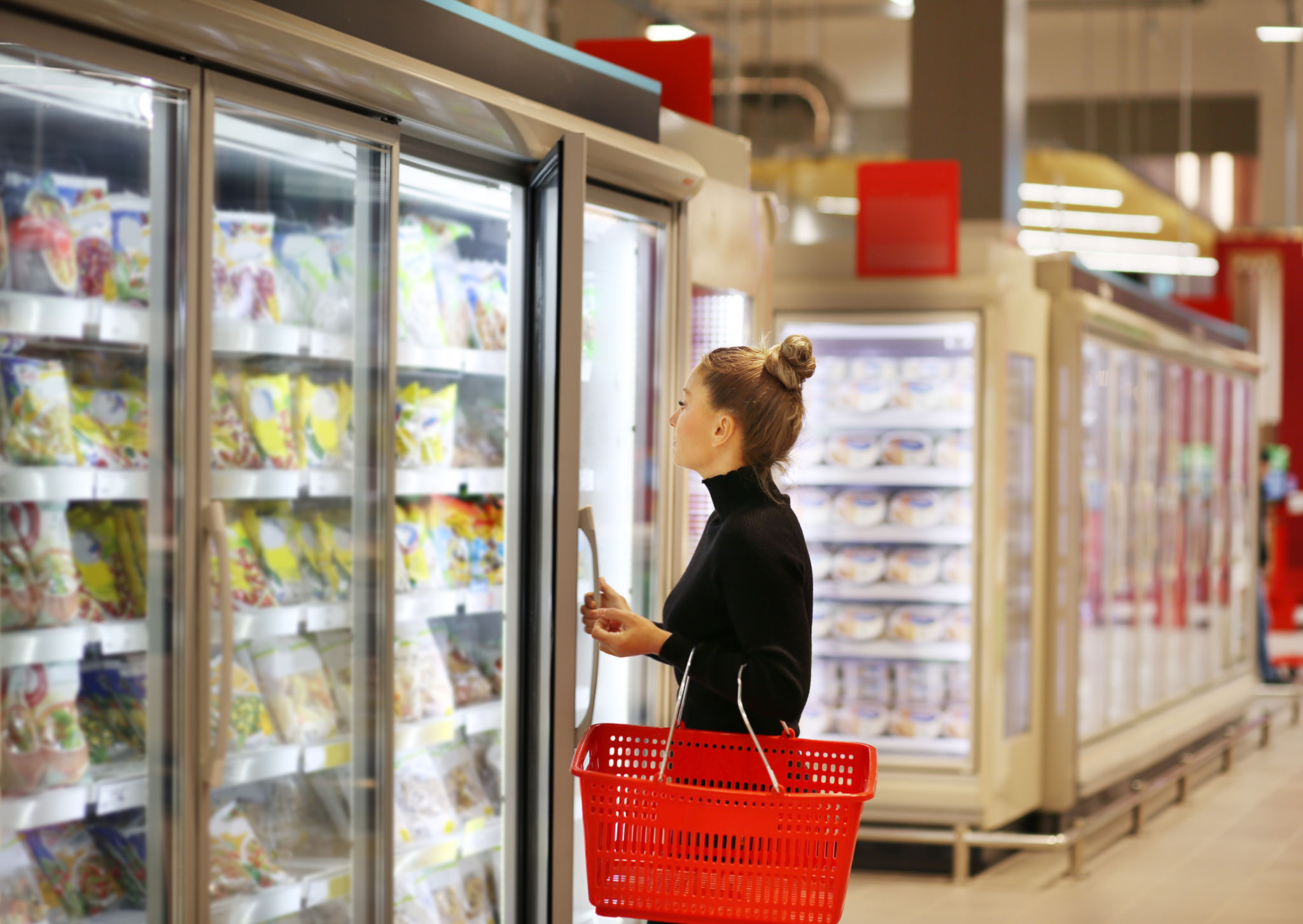 Woman choosing frozen food from a supermarket freezer Woman choosing frozen food from a supermarket freezer