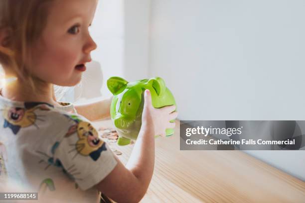 girl shaking piggy bank - perks stock pictures, royalty-free photos & images