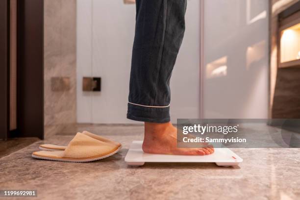 low section of woman standing on weight scale - scale stock-fotos und bilder