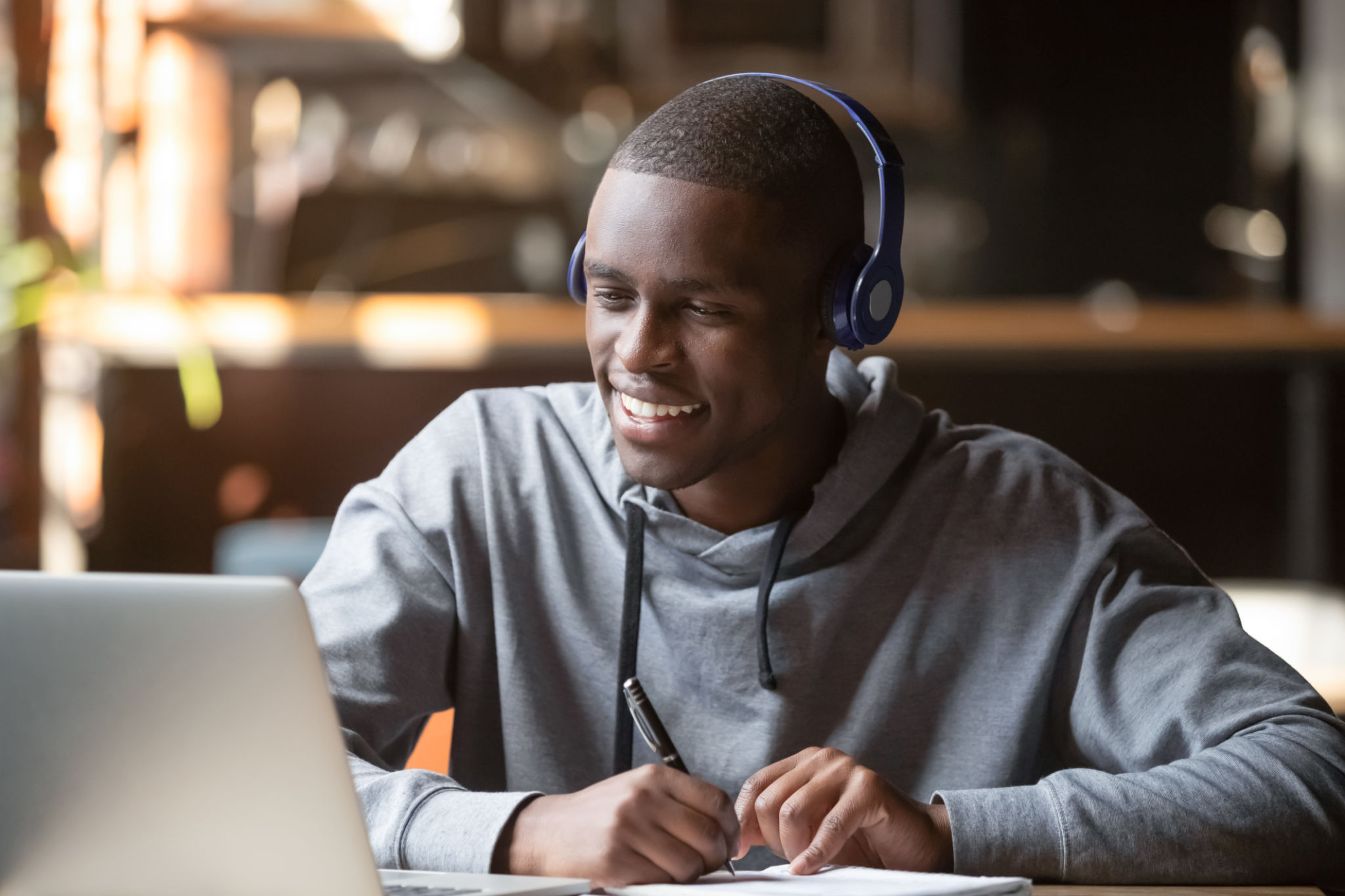 Sonriente africano joven estudiante usando auriculares estudio en línea Sonriente africano joven estudiante usando auriculares estudio en línea