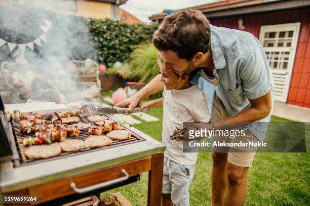 het grillen van vlees met mijn vader - barbecue stockfoto's en -beelden
