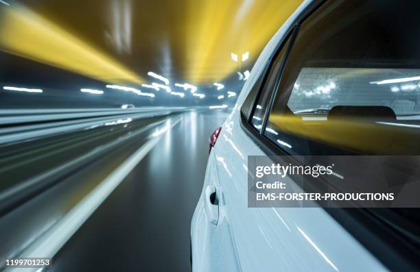 electric white car drives on autobahn while rainy night - rear view. - autobahn stock pictures, royalty-free photos & images