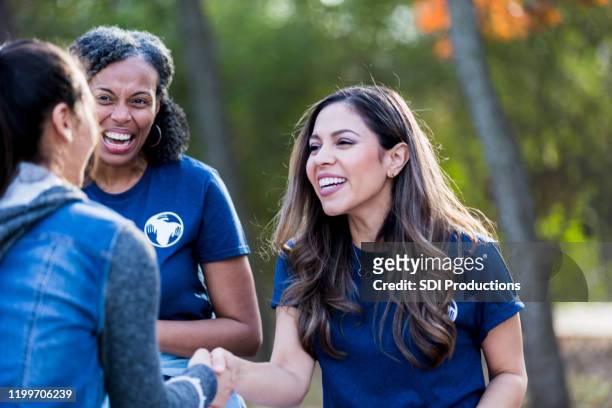 at park cleanup event, two women greet and shake hands - charity and relief work stock pictures, royalty-free photos & images