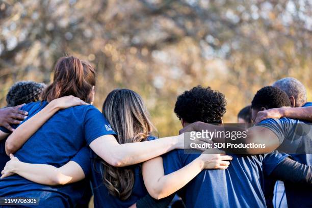 vrienden koppelen armen in eenheid - assistance stockfoto's en -beelden