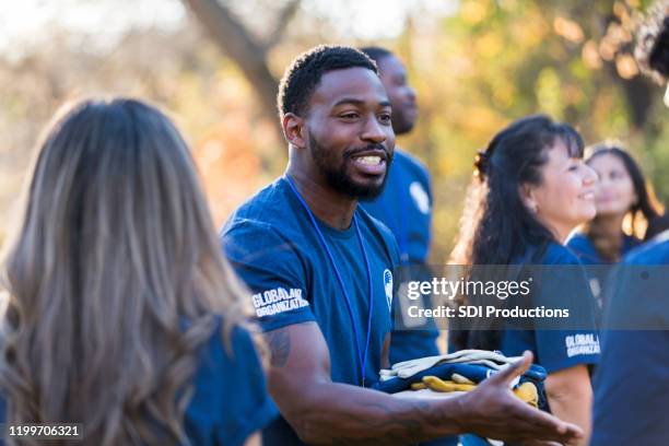 charity event organizer greets volunteer during community cleanup event - organização sem fins lucrativos imagens e fotografias de stock