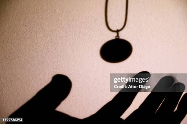 silhouette of human hand with is going to catch a pendant. - locket stock pictures, royalty-free photos & images