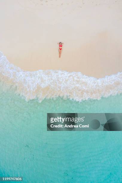 aerial view of a young woman lying down on a beach with turquoise sea. san blas islands, panama - aerial beach view sunbathers stock pictures, royalty-free photos & images