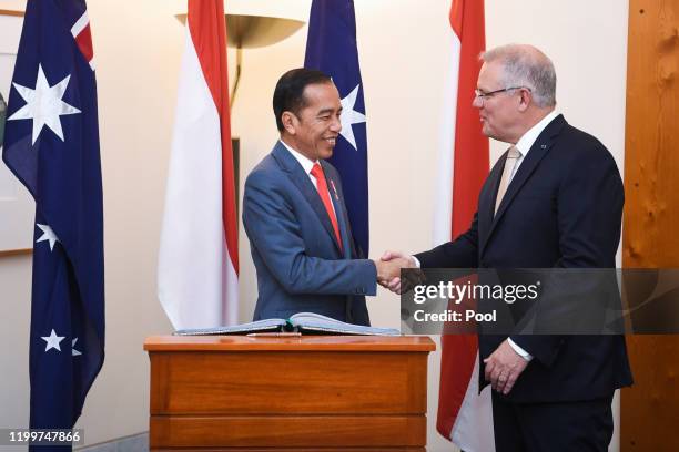 Indonesian President Joko Widodo shakes hands with Australian Prime Minister Scott Morrison after signing the official visitors book at Parliament...