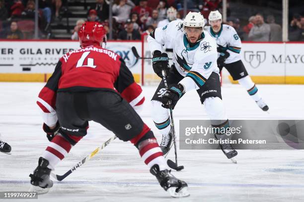 Evander Kane of the San Jose Sharks skates with the puck against Niklas Hjalmarsson of the Arizona Coyotes during the third period of the NHL game at...