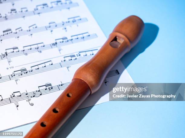 recorder and a sheet music on blue background - flöte stock-fotos und bilder