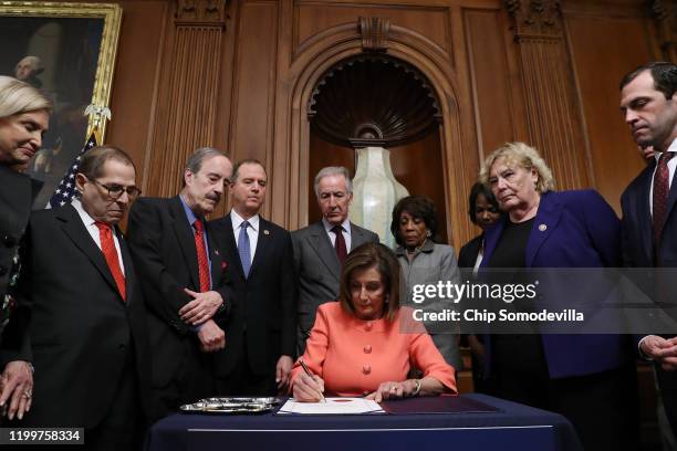 Speaker of the House Nancy Pelosi signs the Articles of Impeachment against President Donald Trump during an engrossment ceremony with Rep. Carolyn...