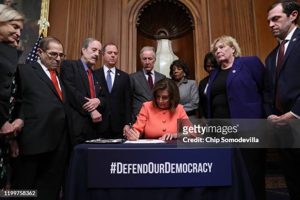 Speaker of the House Nancy Pelosi signs the articles of impeachment against President Donald Trump during an engrossment ceremony with Rep. Carolyn...