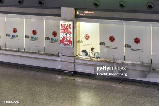 Railway employee sits behind the ticket counter at Hongqiao Highspeed Railway Station in Shanghai, China on Sunday, Feb. 9, 2020. Most Chinese...