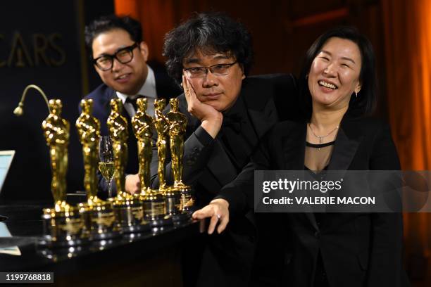 South Korean screenwriter Han Jin-won, South Korean film director Bong Joon Ho and producer Kwak Sin-ae pose with their engraved awards as they...