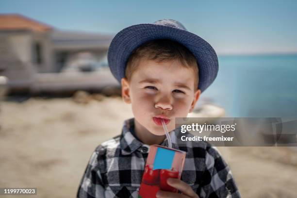 cute boy drinking juice on the beach - juice box stock pictures, royalty-free photos & images