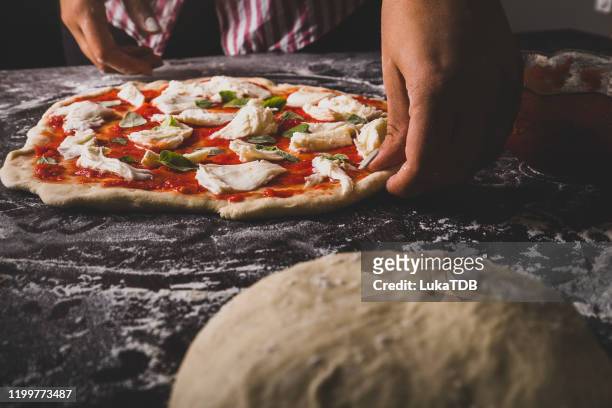 een chef-kok bereidt een kaas en basilicum pizza - zelfgemaakt stockfoto's en -beelden