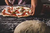 A chef preparing a cheese and basil pizza