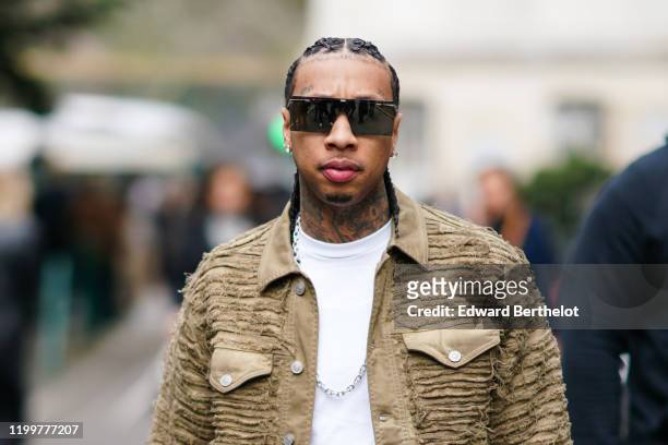 Tyga wears a khaki jacket, a white t-shirt, a chain necklace, sunglasses, outside Y Project, during Paris Fashion Week - Menswear F/W 2020-2021 : Day...