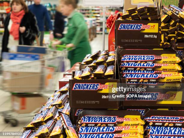 Lots of Snickers chocolate bars by Mars are seen displayed at the store shelf.