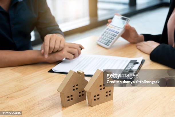 real estate agent discussing interest  rate showing calculator to customer in office. - real estate broker stock-fotos und bilder