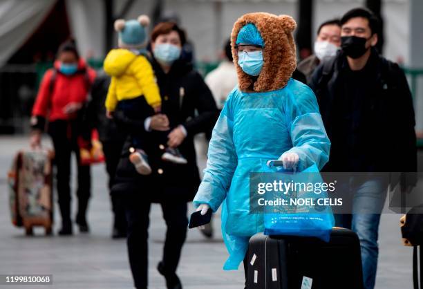 People wearing protective face masks arrive at a railway station in Shanghai on February 10, 2020. - The death toll from the novel coronavirus surged...
