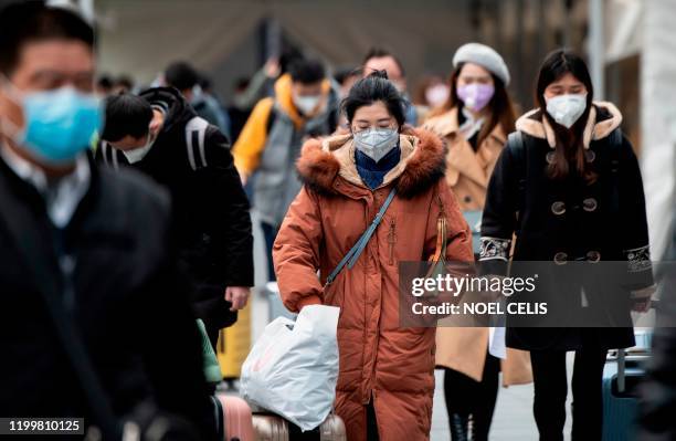 People wearing protective face masks arrive at a railway station in Shanghai on February 10, 2020. - The death toll from the novel coronavirus surged...