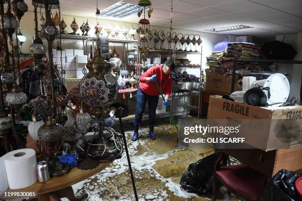 Womman sweeps water from the floor during the clean-up efforts at a business in Hebden Bridge, northern England, on February 10, 2020 after the...